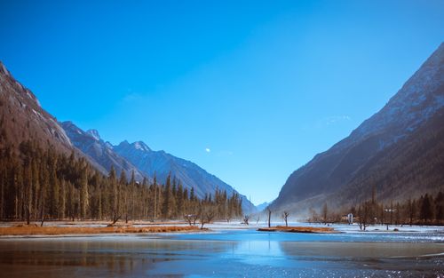 Free Tranquil mountain landscape featuring a clear lake and vibrant blue sky, ideal for nature lovers. Stock Photo