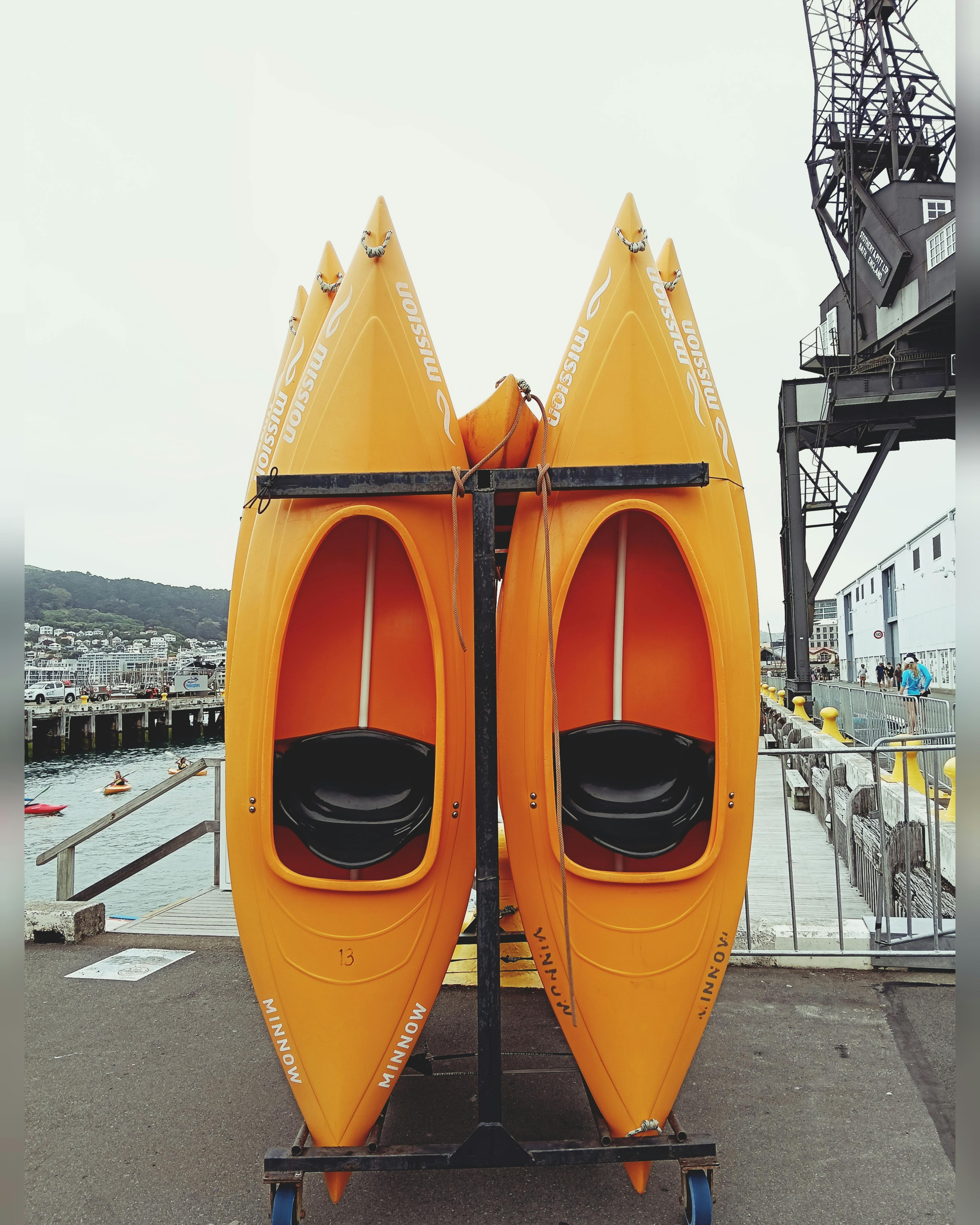 Two bright orange kayaks stacked at a scenic waterfront dock area.