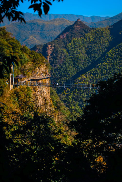 Free Scenic view of a hanging bridge amidst lush green mountains in daylight. Stock Photo