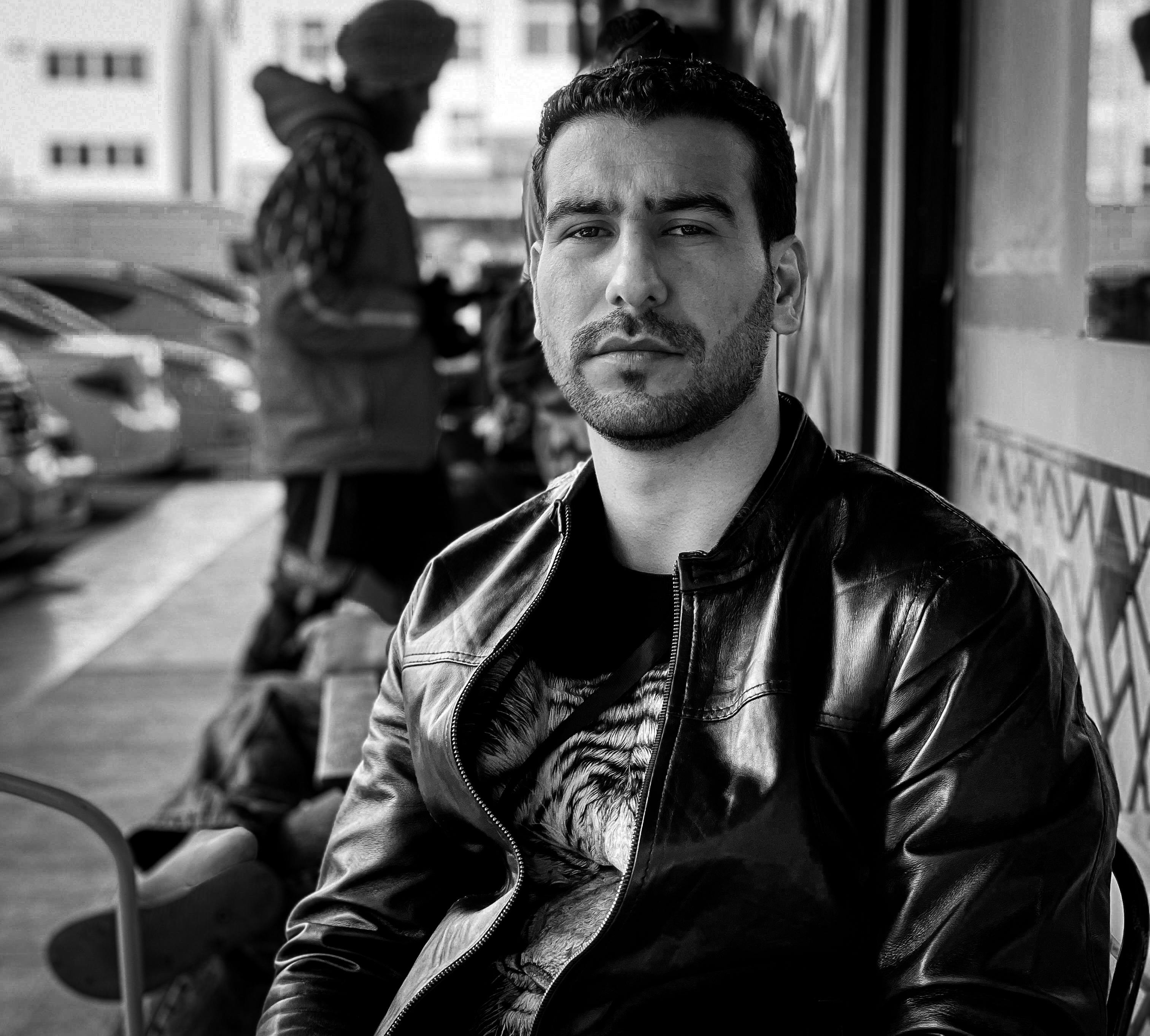 A man in a leather jacket sitting outdoors in Abu Dhabi, UAE.
