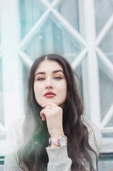 一位长发乌黑的女子，在柔和的自然光下，若有所思地摆着姿势，显得十分宁静