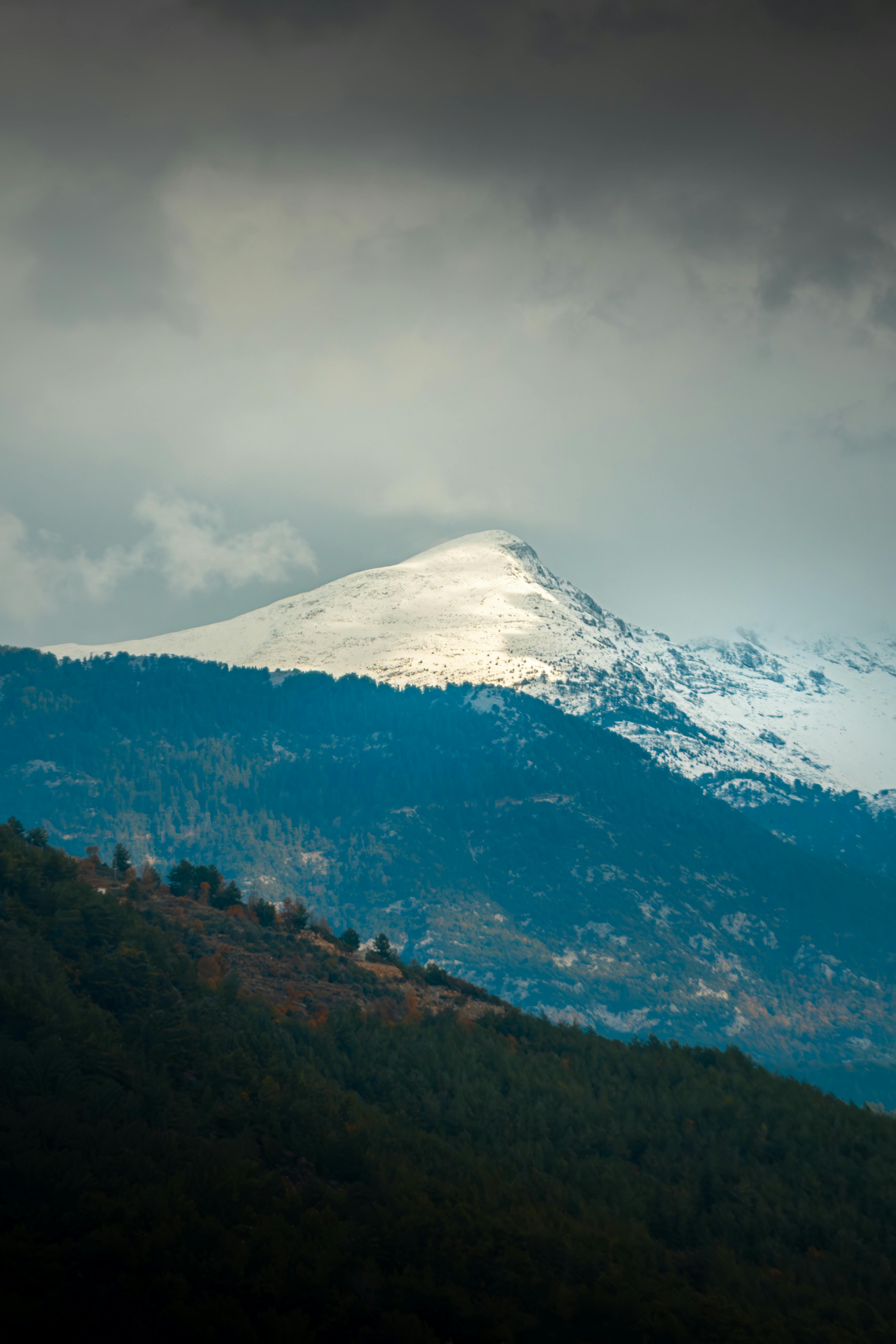 Dramatic view of a snow-capped mountain under cloudy skies in Alanya, Turkey.