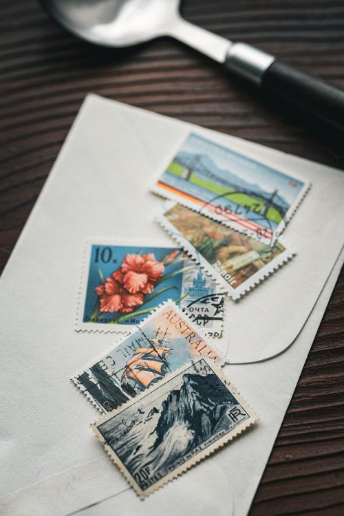 Free Aesthetic flat lay of vintage stamps on envelope with wooden background, perfect for postal themes. Stock Photo