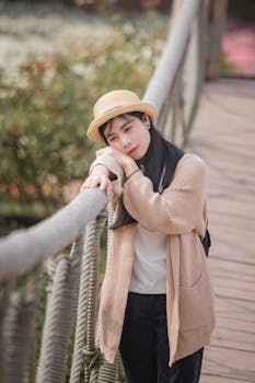 一个女人穿着休闲装，在户外靠在质朴的绳索桥上