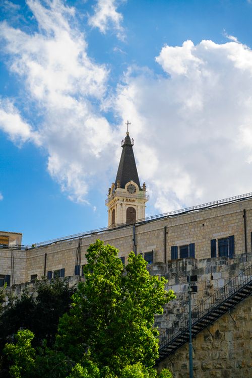 Free A scenic view of a historic stone tower under a vibrant blue sky with clouds. Stock Photo