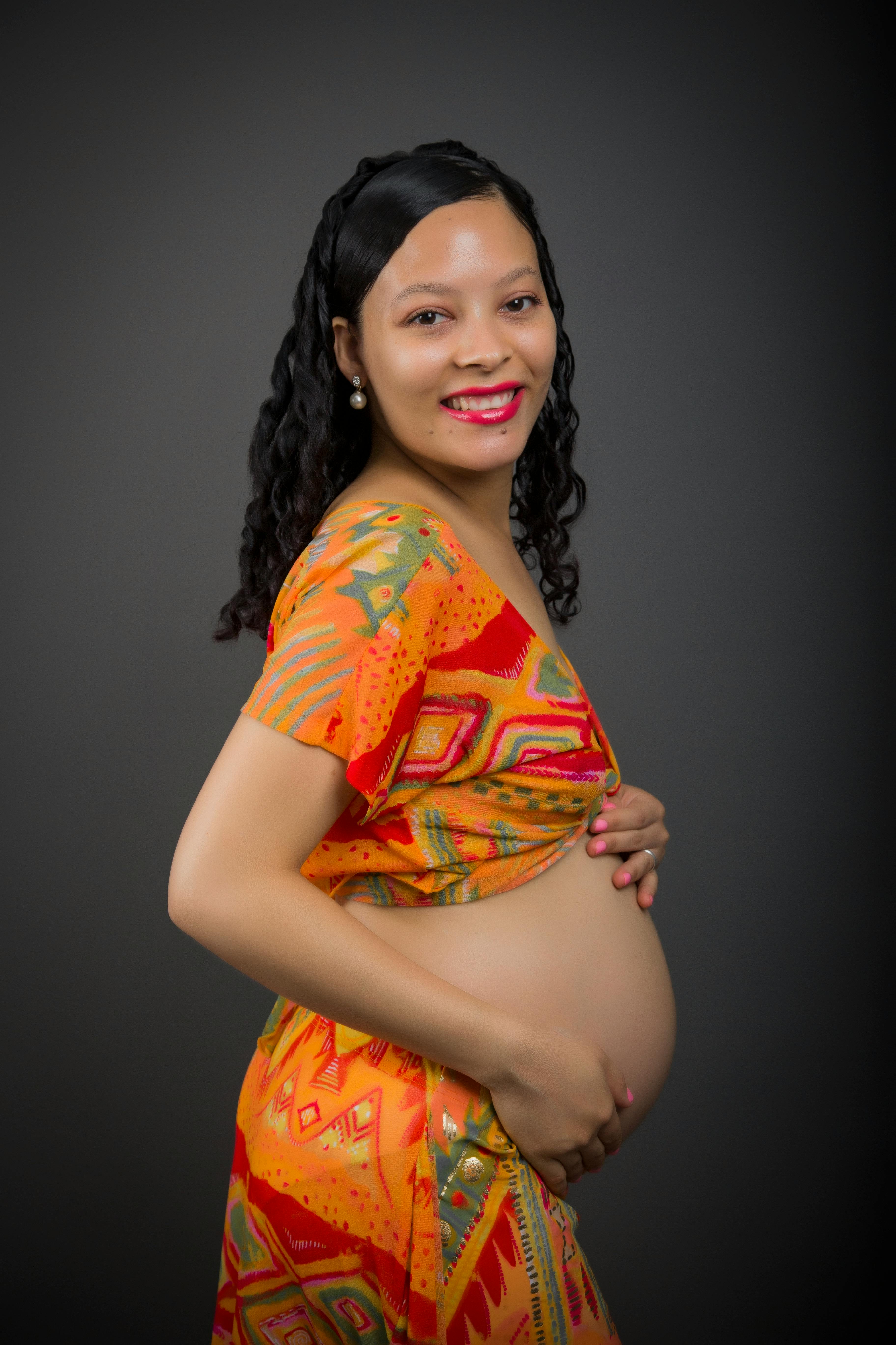 Kostenlos Eine glückliche, schwangere Frau in farbenfroher Kleidung posiert in einem Studio. Stock-Foto