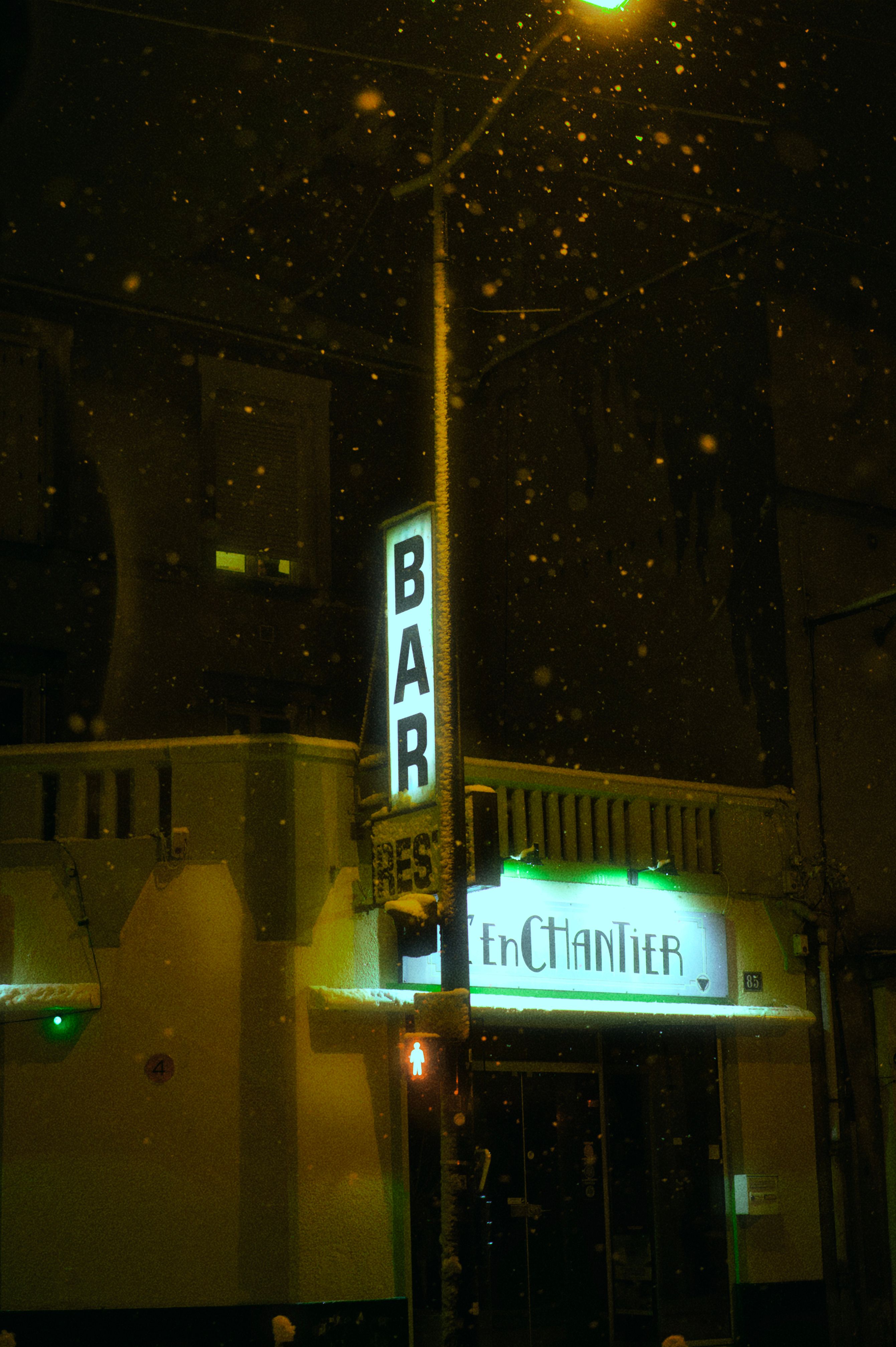 grátis A entrada acolhedora e convidativa do bar é iluminada à noite por flocos de neve que caem suavemente. Foto profissional
