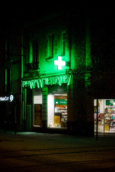 Cruz de farmacia iluminada en verde de noche