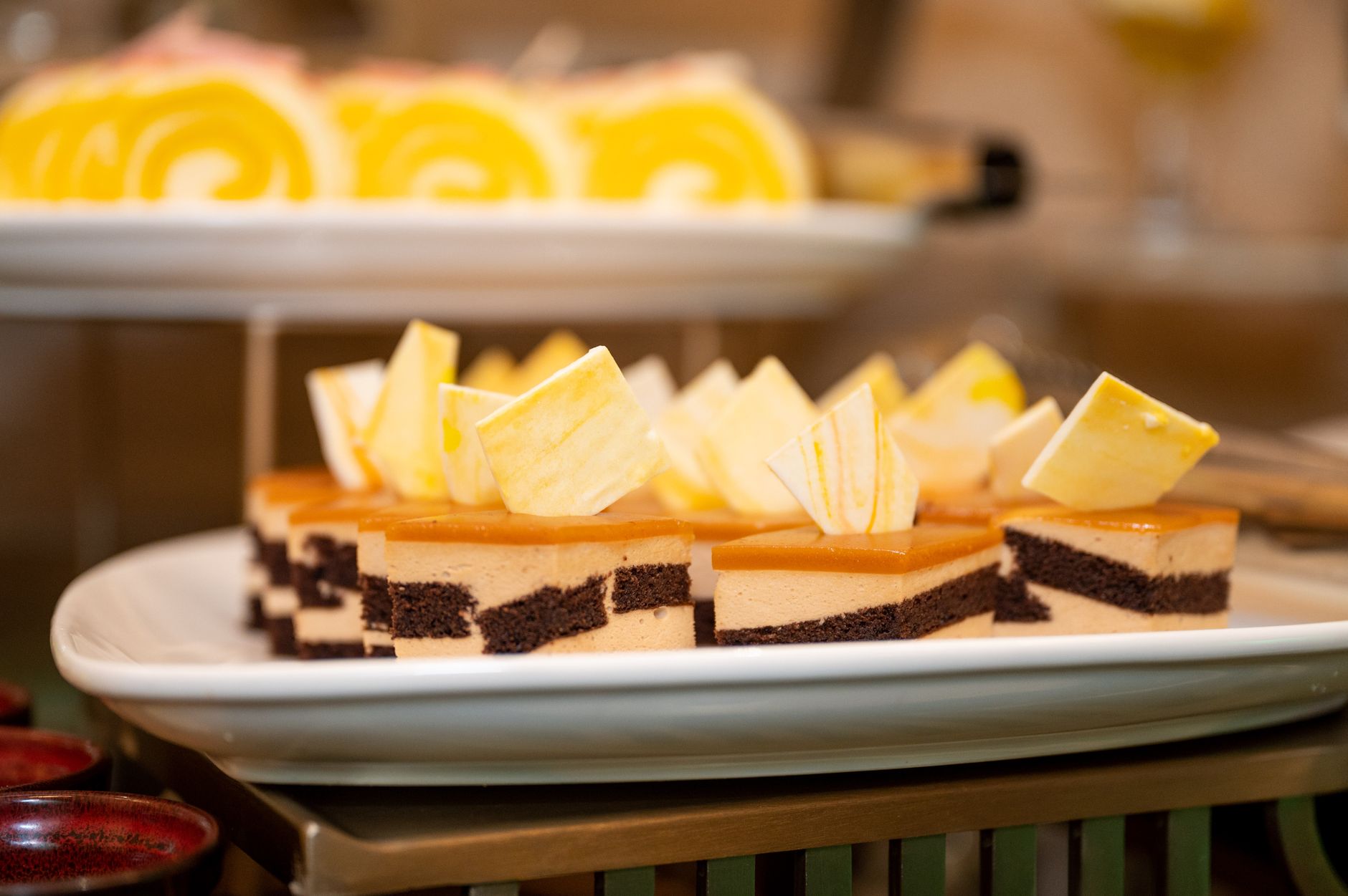 Exquisite chocolate and caramel layered pastries garnished with white chocolate on a serving plate.