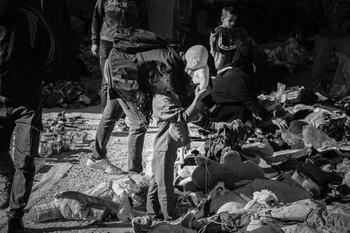 Free A young girl in a busy outdoor market holds a doll amidst a busy, vibrant scene. Stock Photo