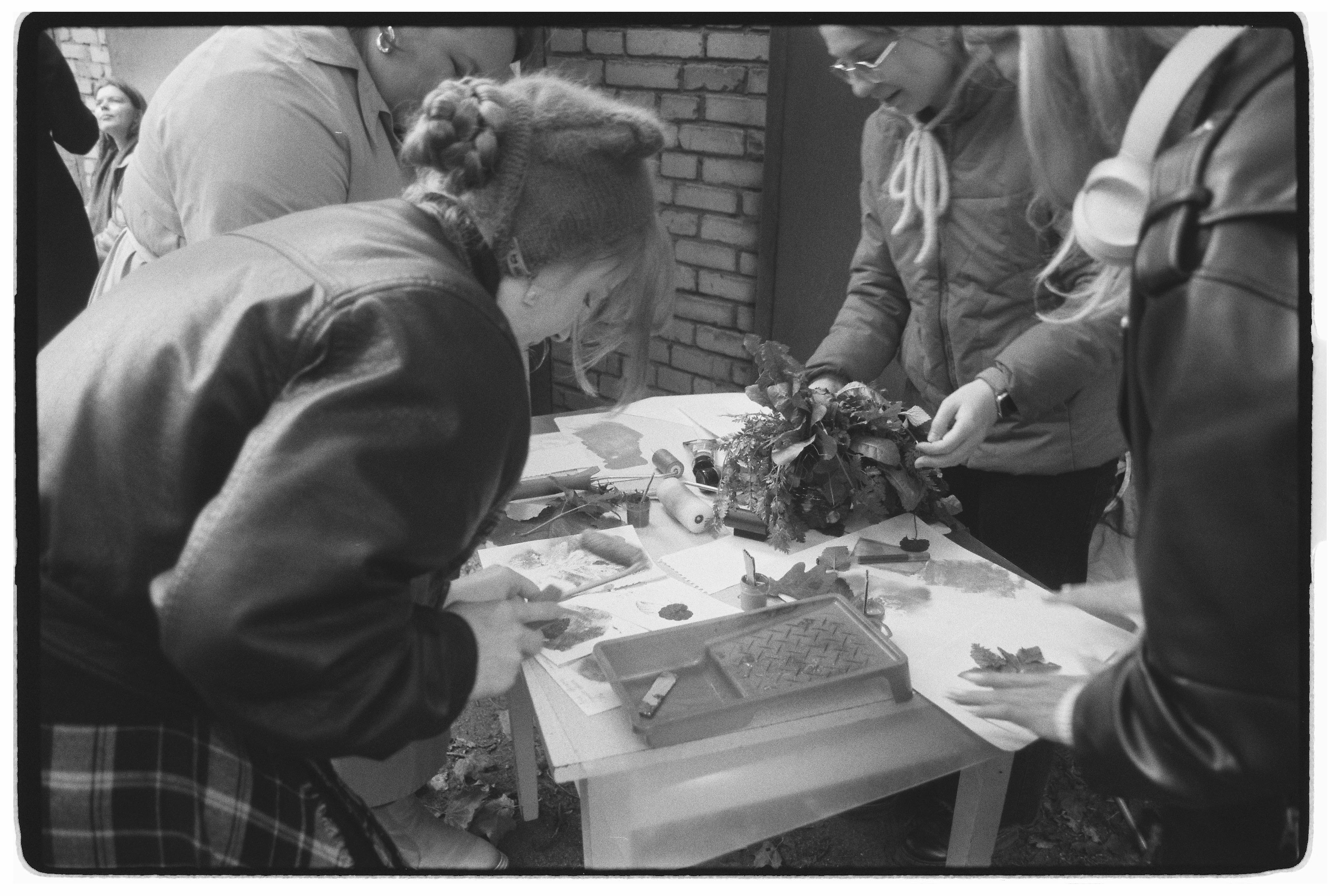 A group of people engaged in an outdoor craft workshop, creating with natural materials.