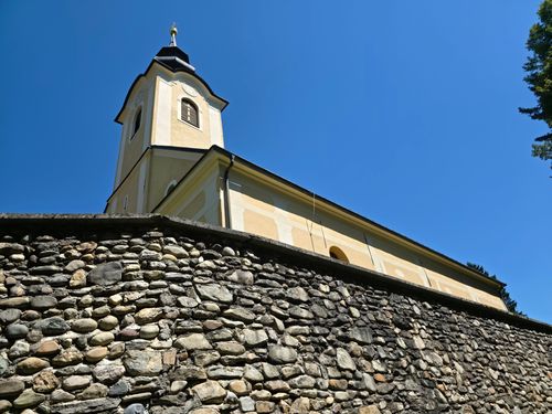 Free A picturesque view of a church tower with stone wall under clear blue sky. Stock Photo