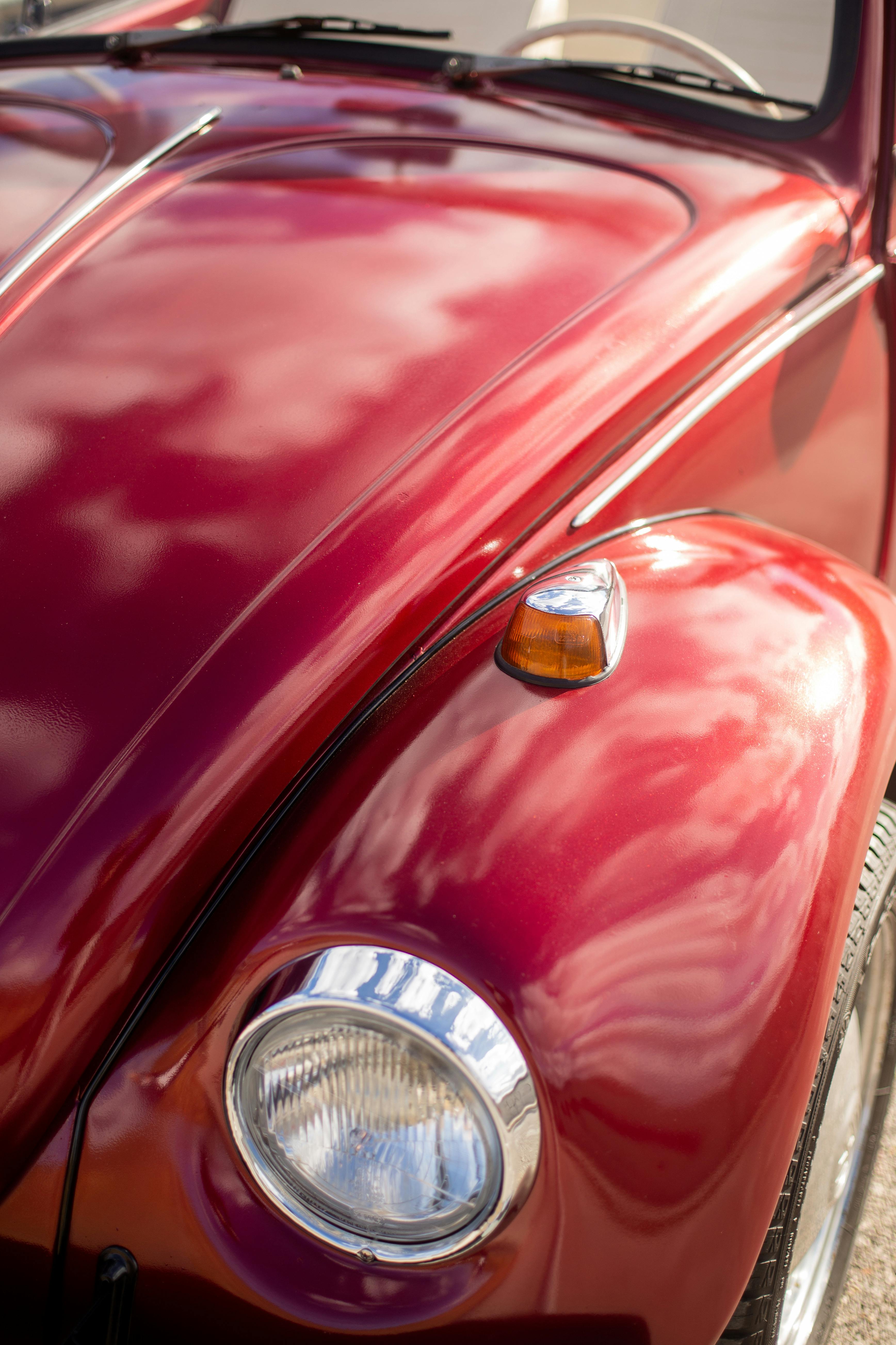 De franc Primer pla d'un cotxe vermell clàssic amb un capó reflectant brillant que mostra reflexos del cel. Foto d'estoc