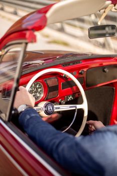 Driver enjoying a ride in a classic red convertible with a vintage dashboard view.