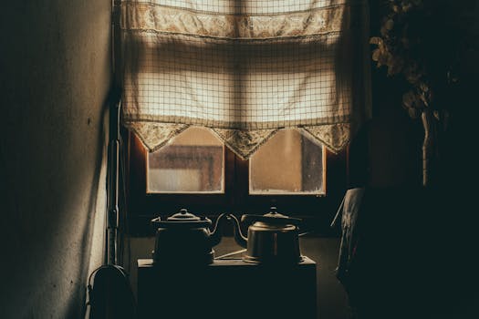 Cozy vintage kitchen scene with teapots silhouetted against warm window light, evoking nostalgia.