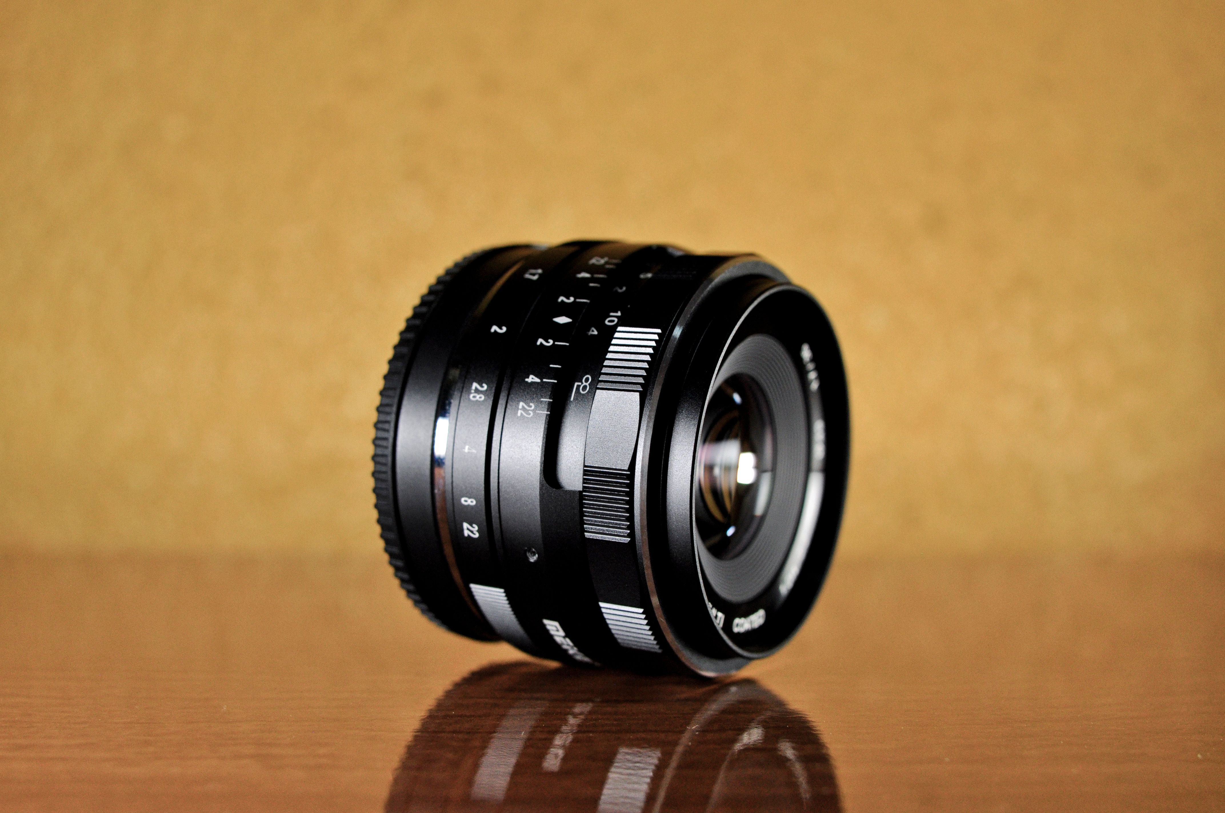 Close-up of a Camera Lens on a Reflective Surface · Free Stock Photo