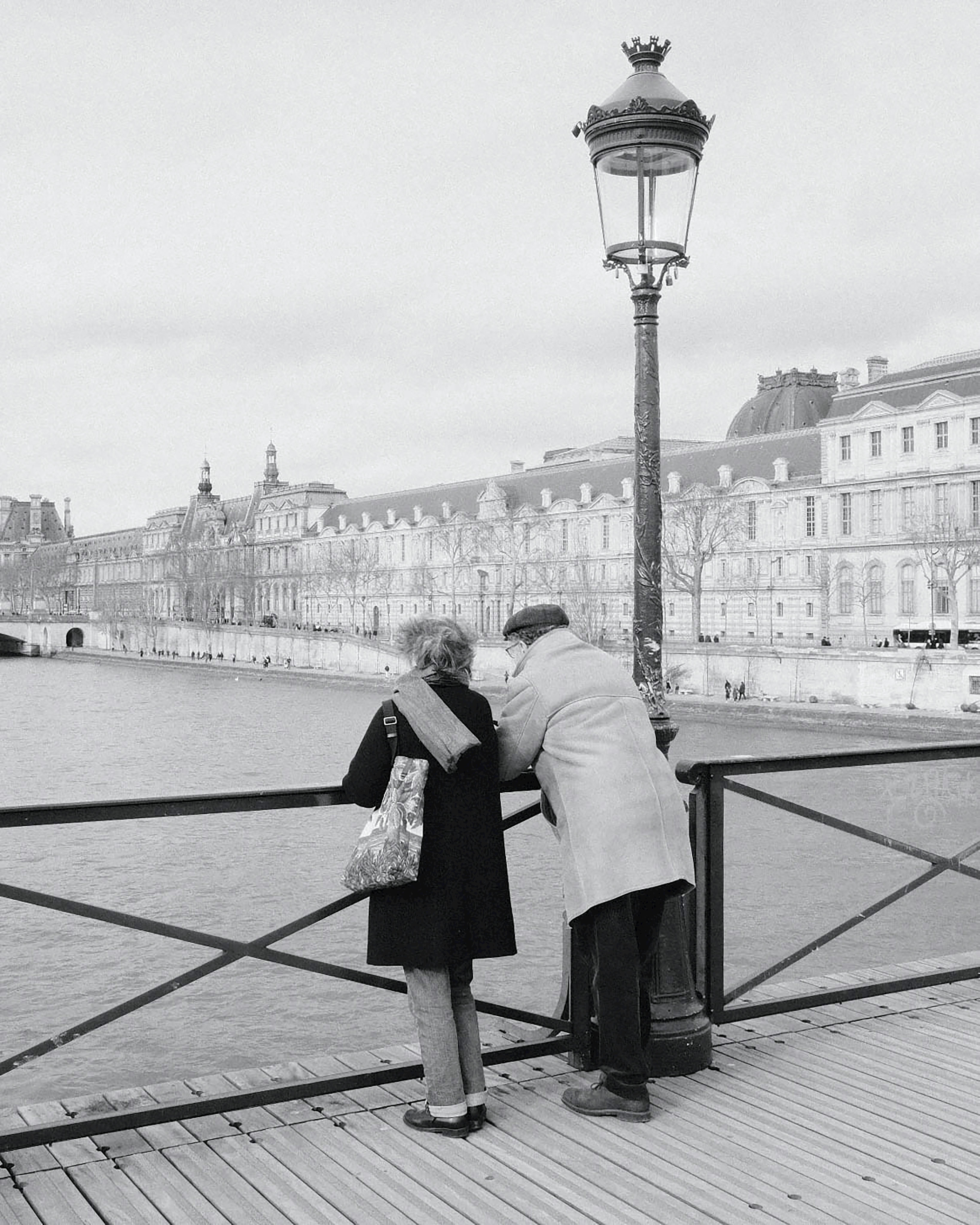 A senior couple embraces while gazing across the Seine River in Paris, France.
