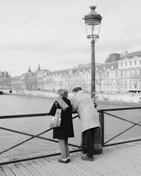 A senior couple embraces while gazing across the Seine River in Paris, France.