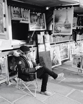 Monochrome photo of a street artist in Paris by the Eiffel Tower displaying artwork.