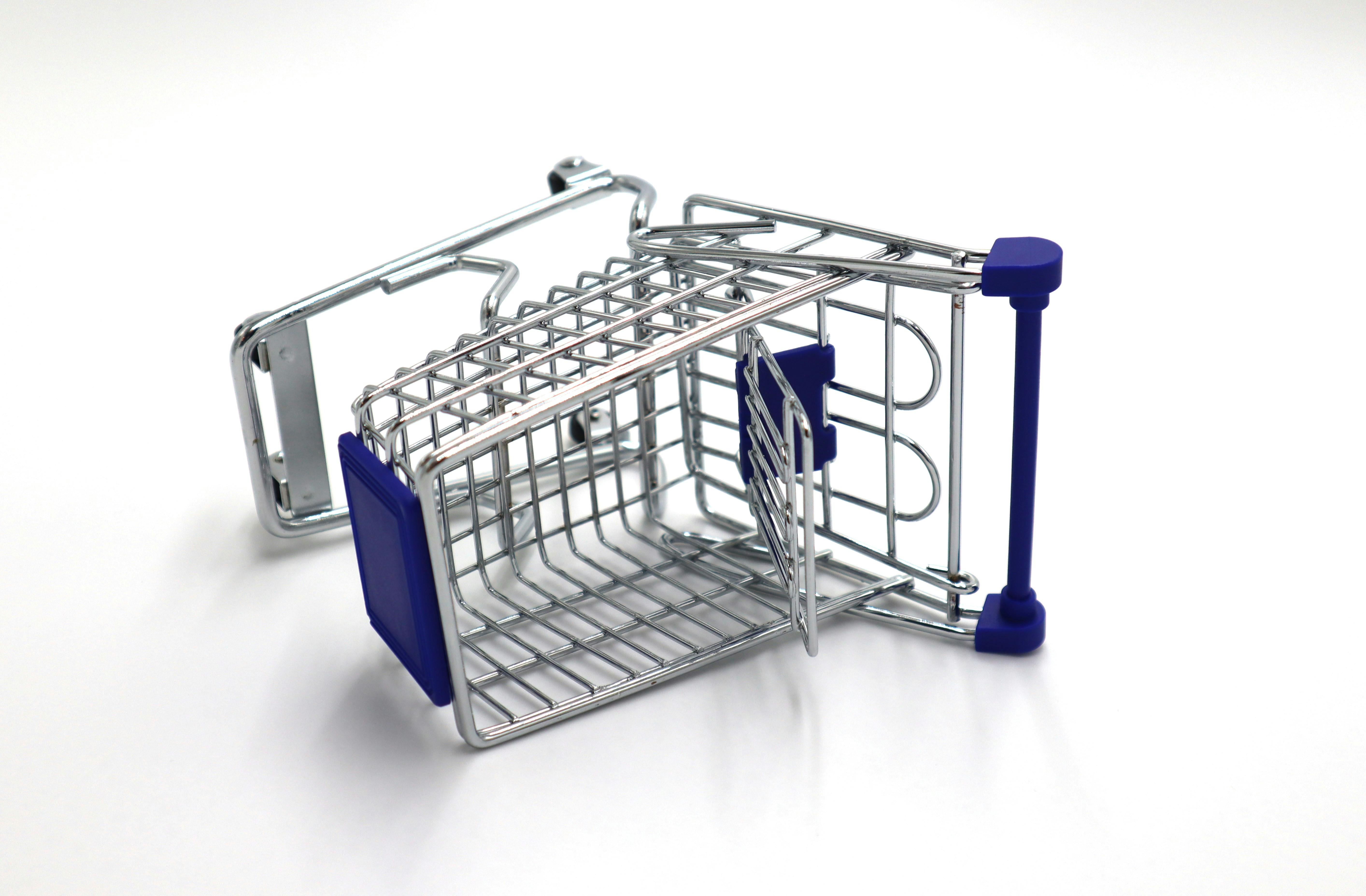 A small overturned shopping cart against a white backdrop, depicting economic challenges.
