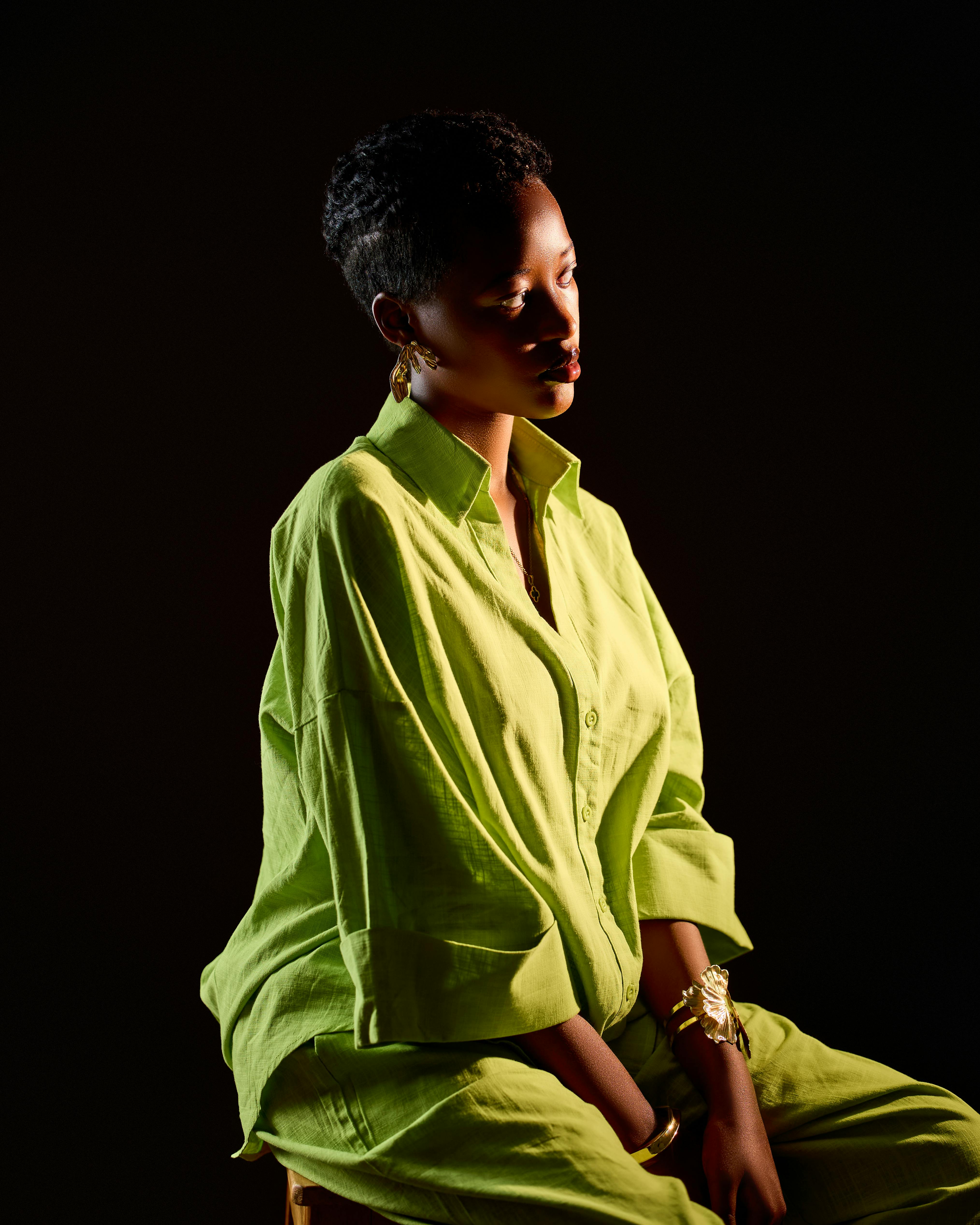Artistic portrait of a woman in a lime green outfit against a dark background.