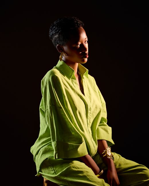 Artistic portrait of a woman in a lime green outfit against a dark background.
