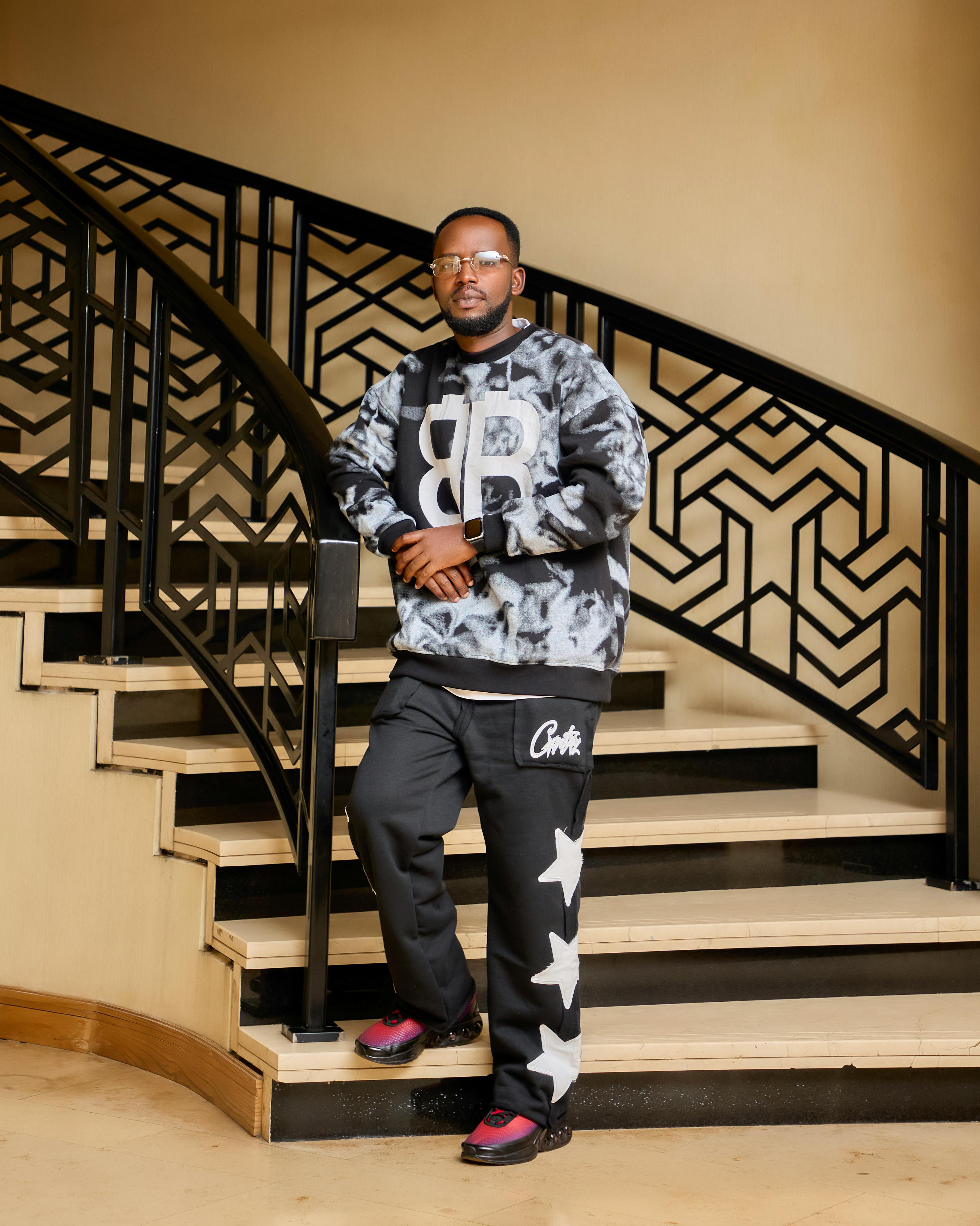 Fashionable man in casual attire stands confidently on an elegant Art Deco staircase indoors.