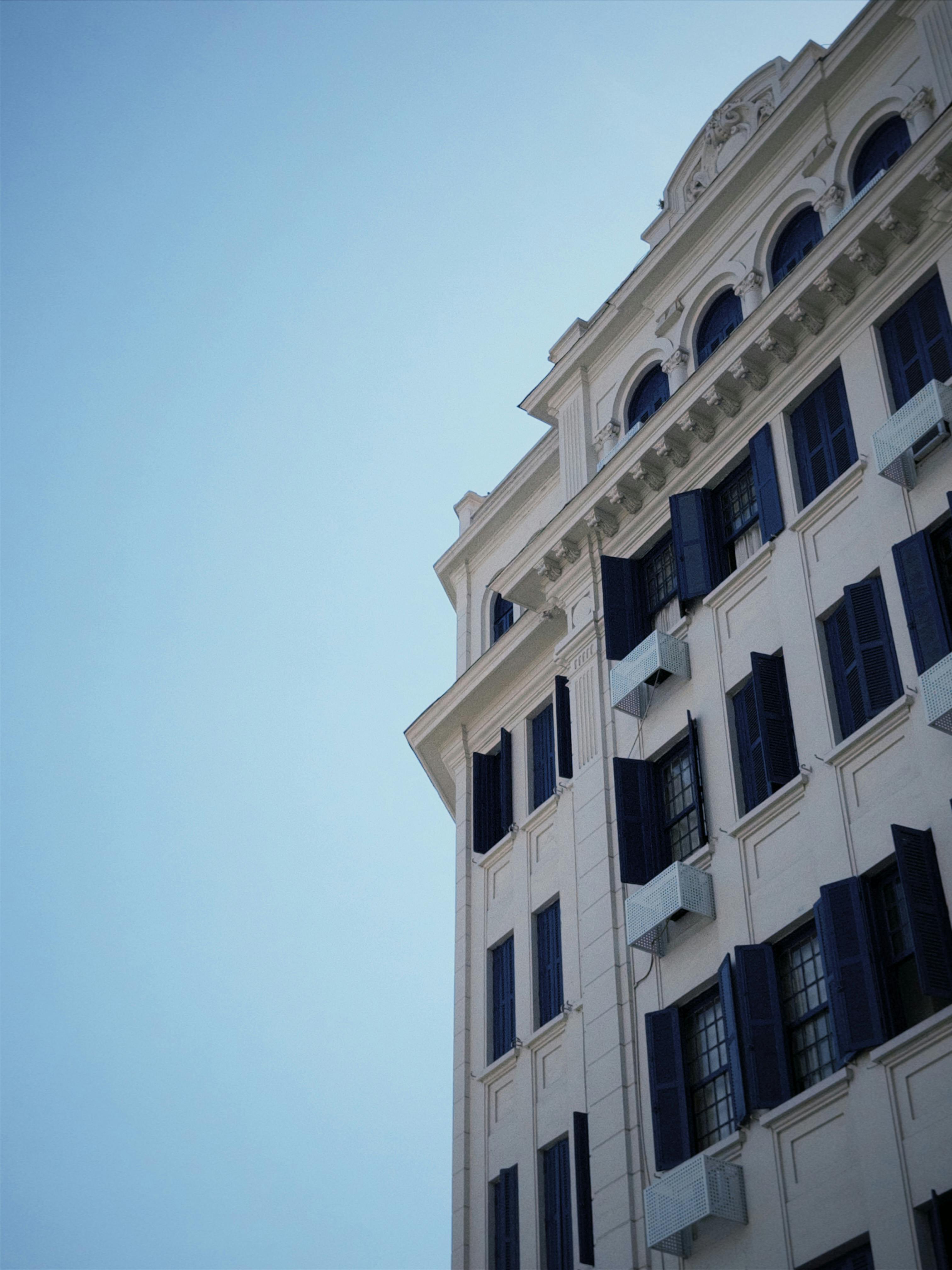 Gratis Elegant historisk bygning med klassisk arkitektur og blå skodder mod en klar himmel, der tilbyder en følelse af ro og nostalgi. Lagerfoto