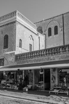 Black and white image of a historic street market with stone buildings and shops.