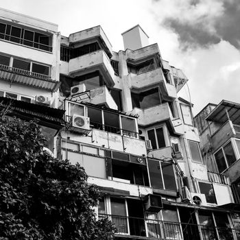 Monochrome architectural photo showing a worn apartment building with unique geometric design.