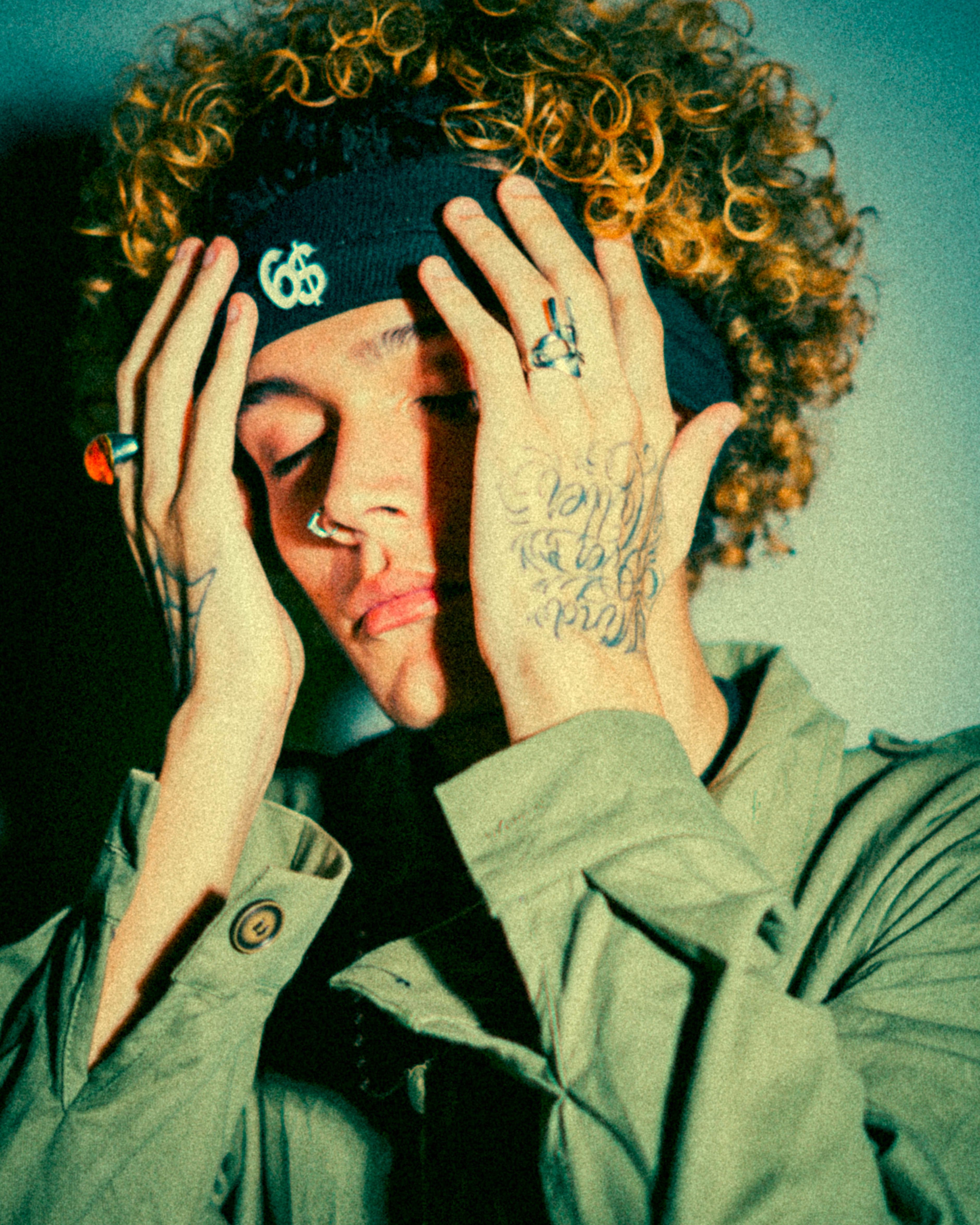 Portrait of a young man with curly hair and tattoos in deep contemplation, expressing emotion.