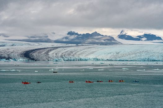 Adventurers kayaking near Vatnajökull Glacier in Iceland's dramatic landscape.