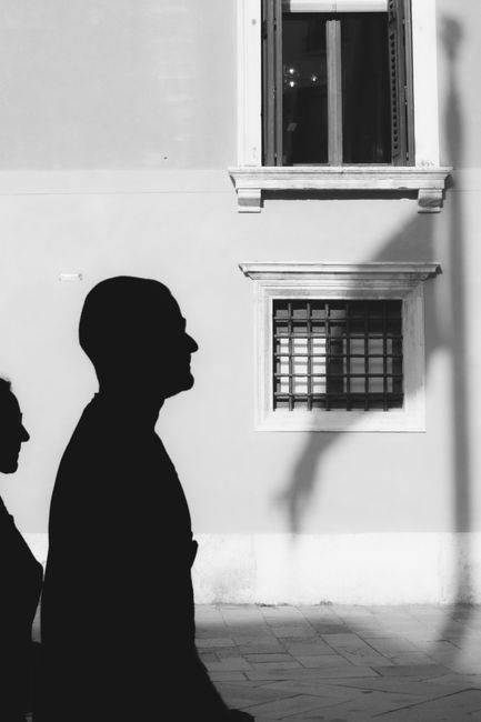 Black and white image capturing silhouettes of people in front of a historic building.