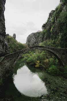 A tranquil scene of an ancient stone bridge spanning a lush gorge.