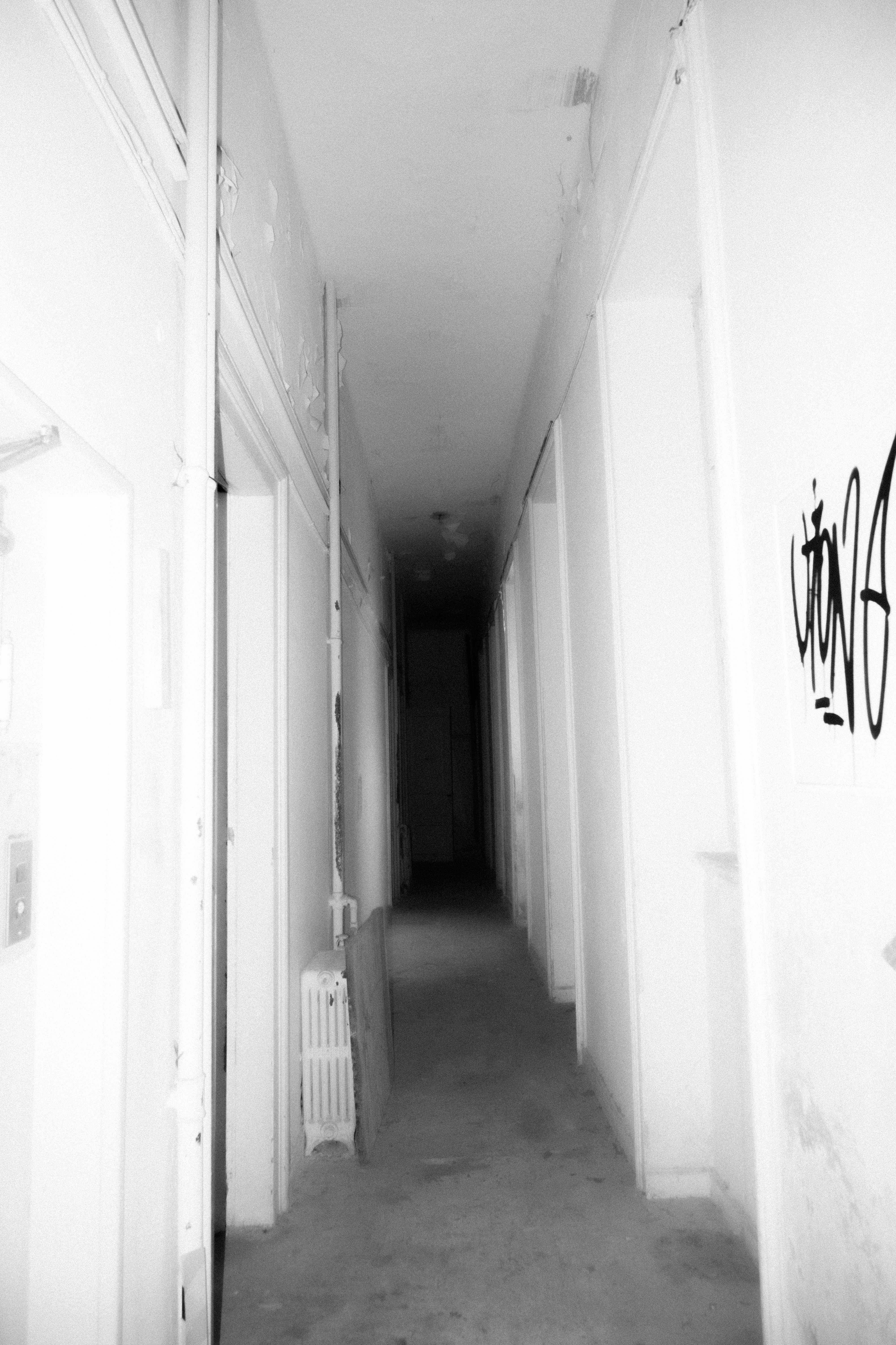 Gritty black and white photo of an eerie abandoned hallway with graffiti.