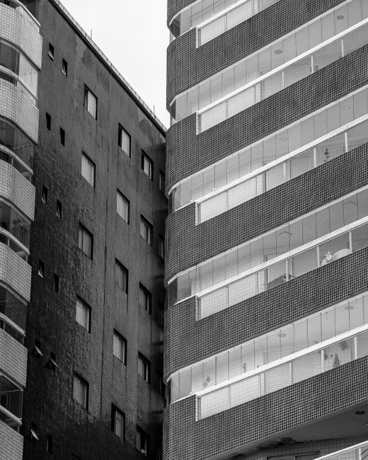 Black and white photo of two contrasting buildings, showcasing modern and classic architecture.