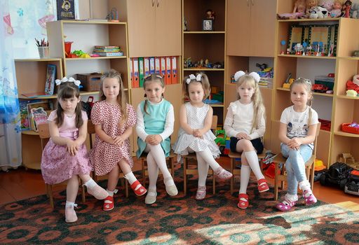 Group of girls sitting in a classroom setting with toys around them.