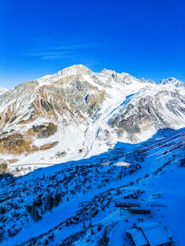 A breathtaking aerial shot of snow-covered Austrian Alps under a clear blue sky.
