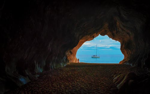 Cave Near Body of Water With Boat