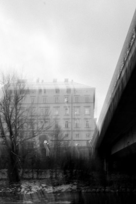Blurred black and white cityscape with trees and building in winter.