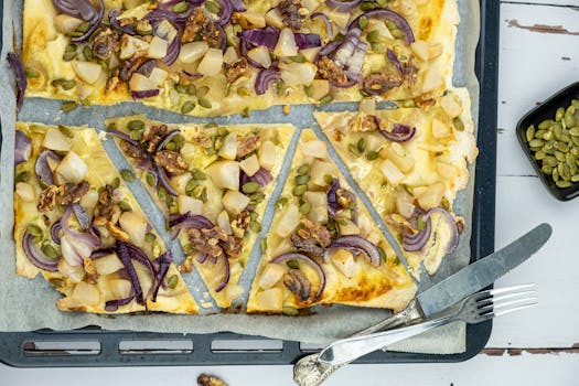 Freshly baked flammkuchen with a variety of gourmet toppings on a baking tray.