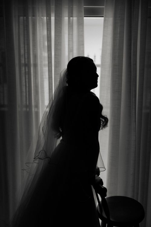 Free Elegant black and white silhouette of a bride standing by a window, creating a romantic mood. Stock Photo