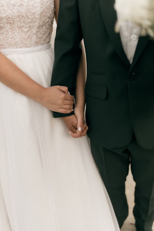 Free Close-up of a bride and groom holding hands in a loving embrace, elegant wedding attire. Stock Photo