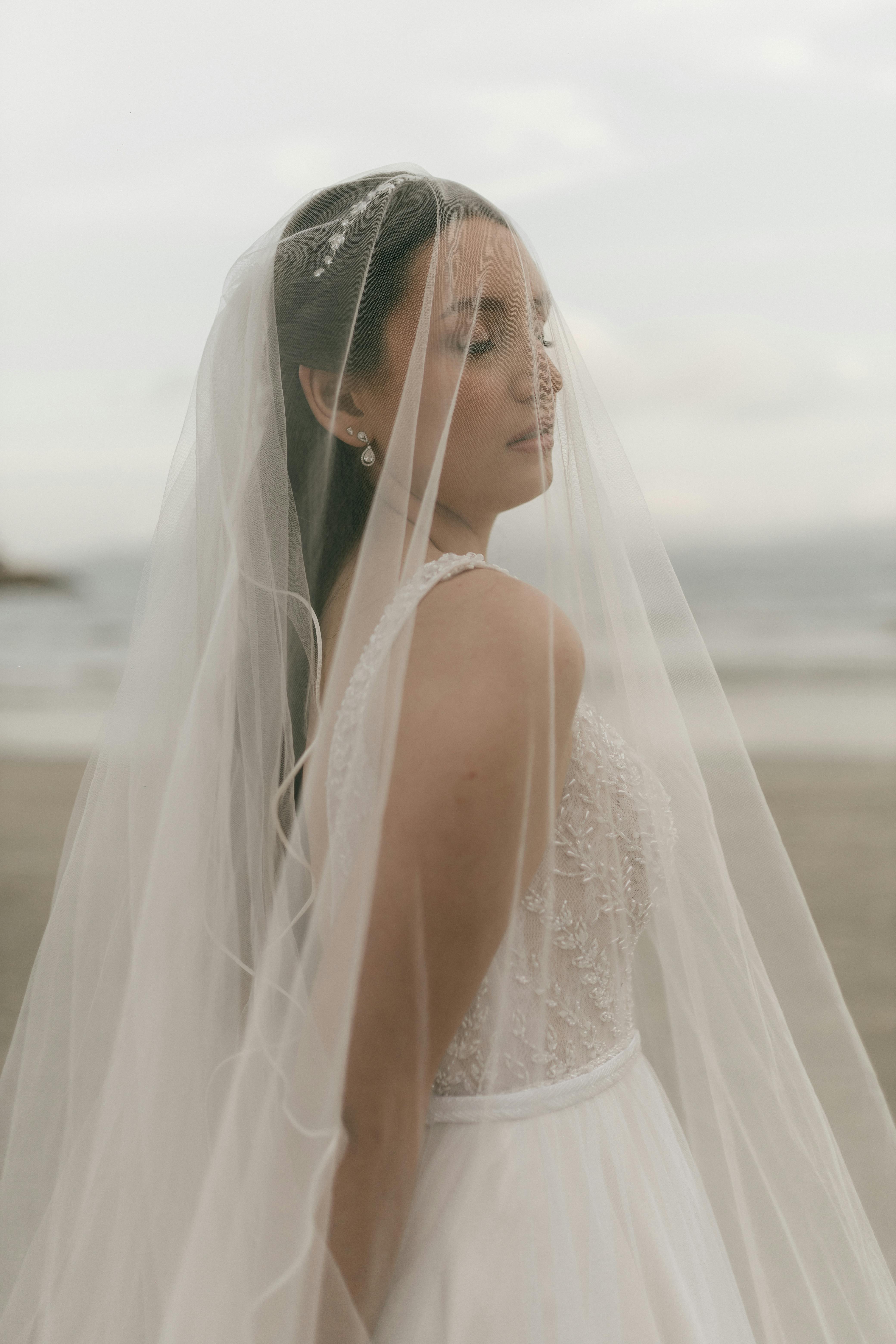 De franc Una bella núvia es troba a la platja, embolicada amb un vel delicat, que traspua elegància i calma. Foto d'estoc