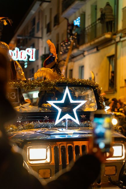 Fotomural Un vibrante desfile nocturno con un Jeep decorado y una estrella iluminada. Capturado en un animado entorno urbano.