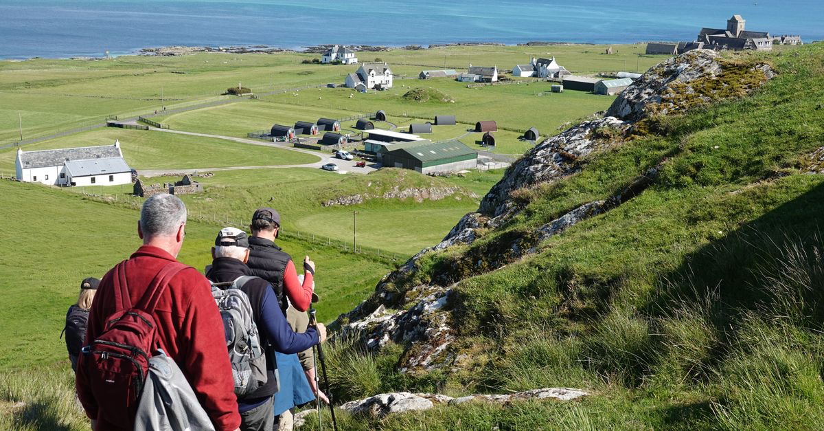 A peaceful view of the Scottish island of Iona with a small stone cross in the foreground