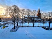 Winter scene with a church and snow-covered trees at sunset.