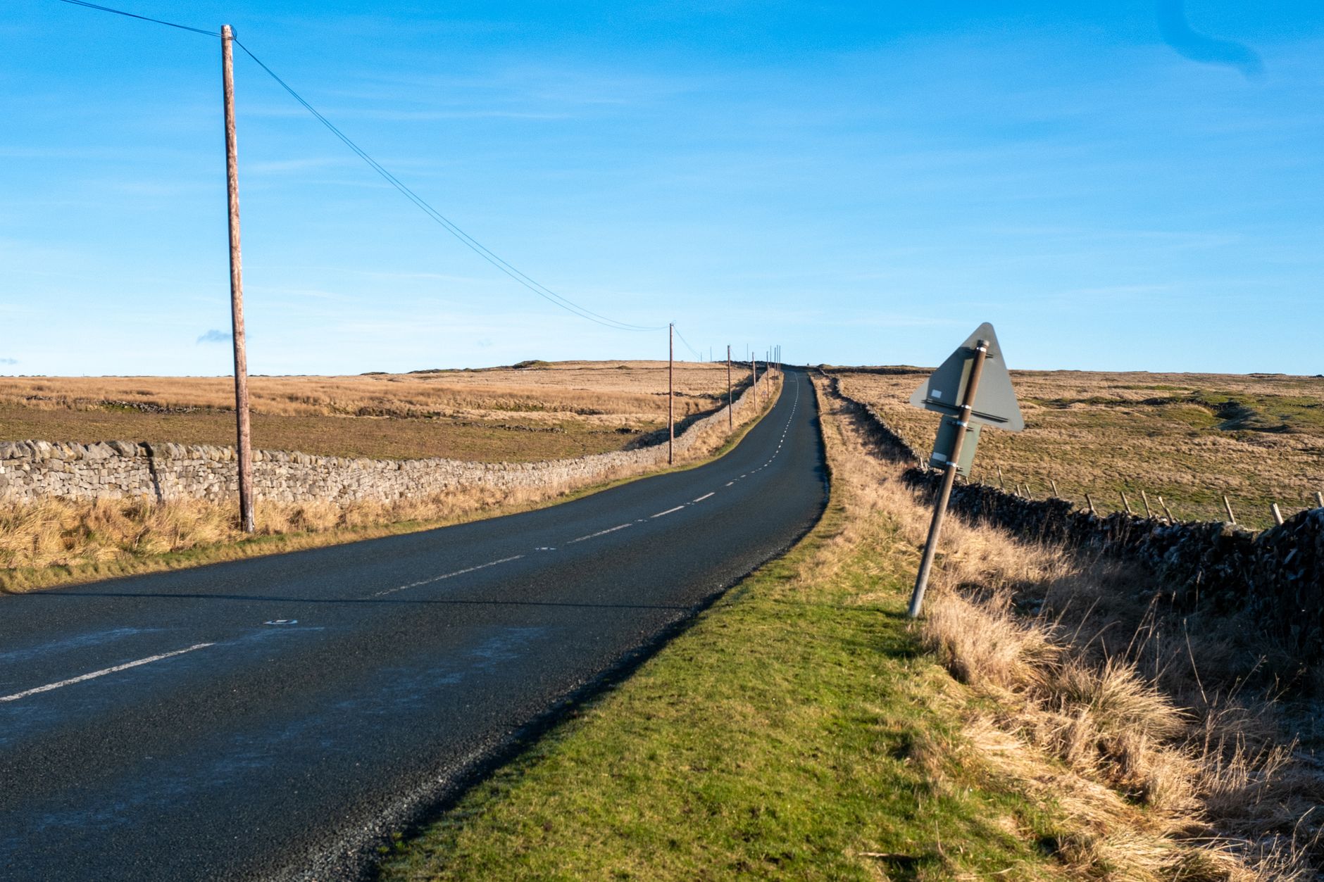 A quiet road winding through the scenic landscape of Greenhow Hill in Yorkshire Dales, England.