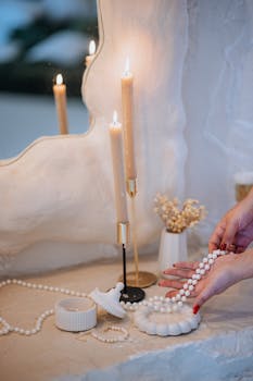 Close-up of a vanity setup with lit candles, pearls, and decorative items creating an elegant ambiance.