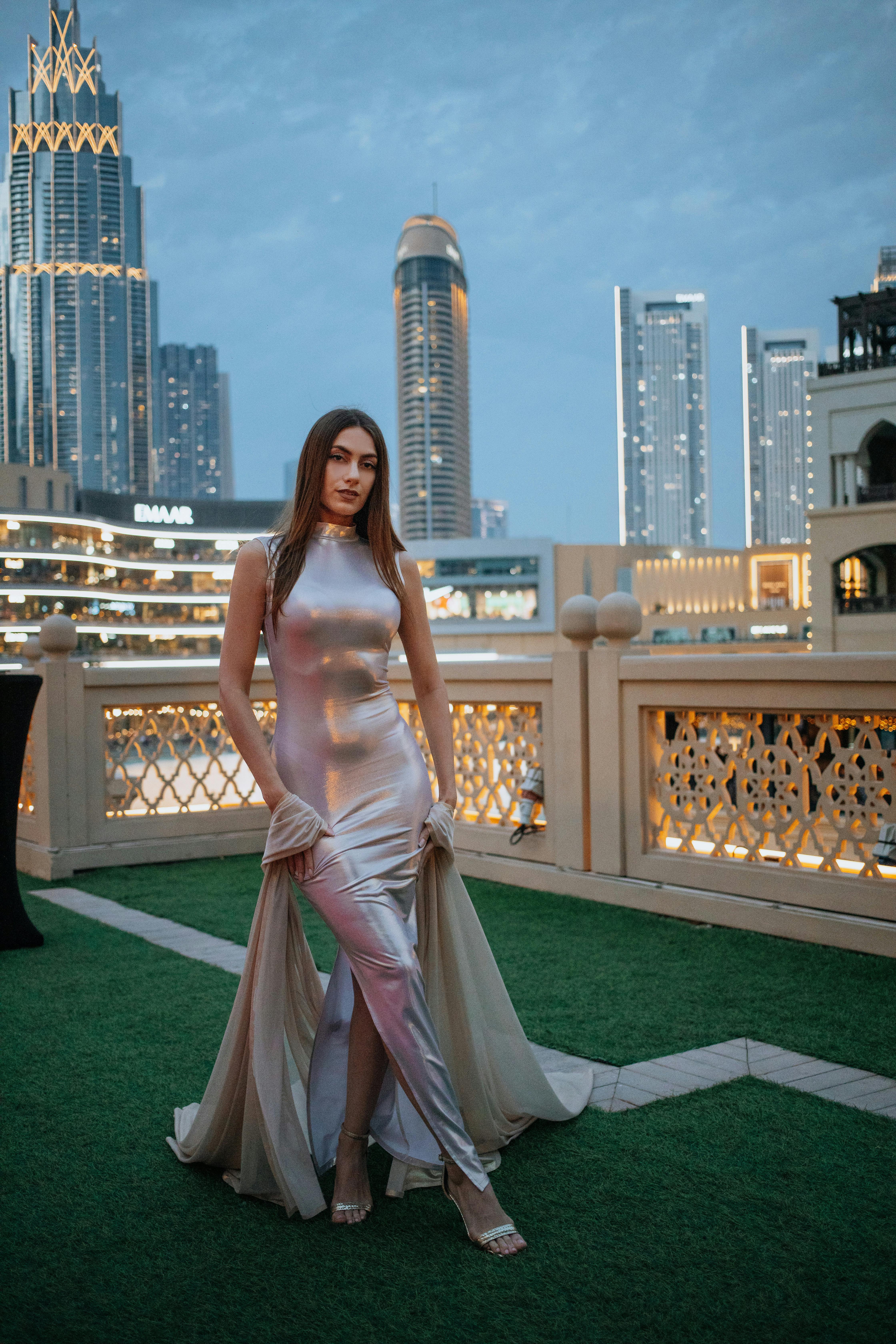 De franc Dona elegant amb un vestit brillant posant al port esportiu de Dubai amb l'horitzó de la ciutat com a teló de fons. Foto d'estoc